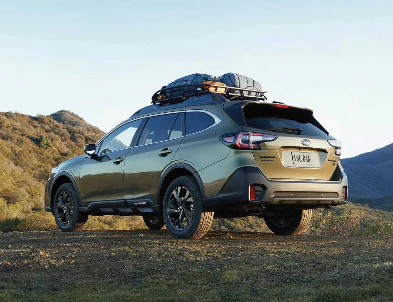 subaru outback parked on a dirt road with a rooftop cargo carrier