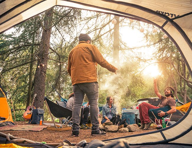 the view from inside a tent of a group of people sitting around a stone fire pit