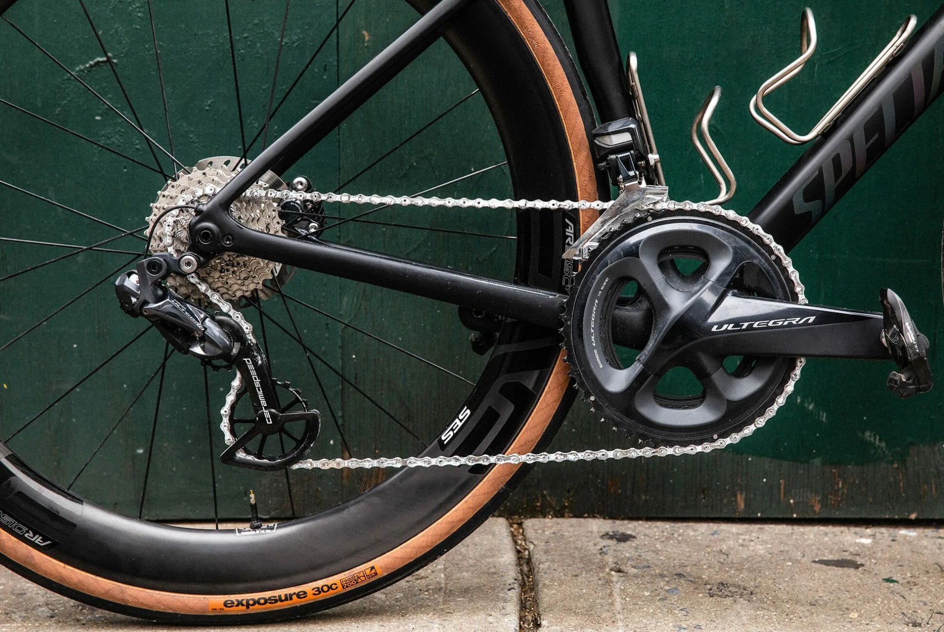 a close up of the gears, chain, derailleur, rear wheel and pedals of a black bicycle