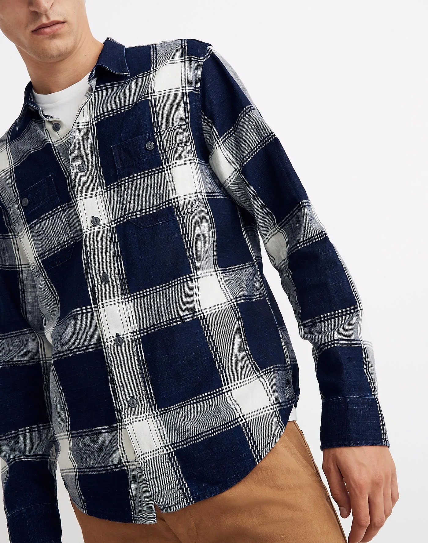 A blue and white checked flannel shirt on a model on a gray background.