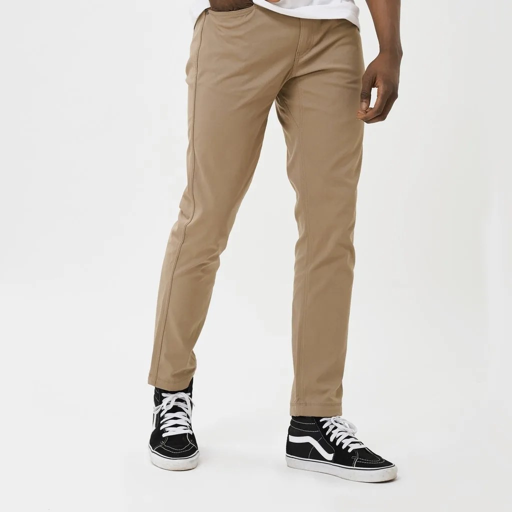 Khaki pants on a model with black high-top sneakers on a gray background.