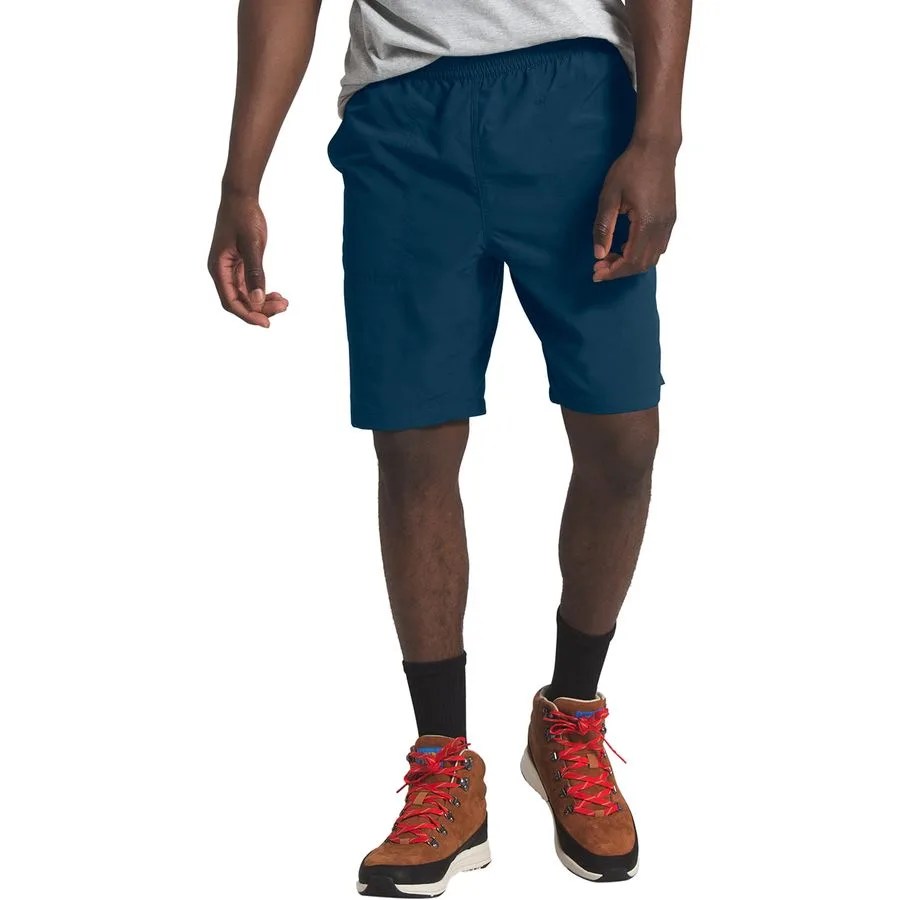 a waist down image of a man wearing navy blue shorts and brown hiking boots