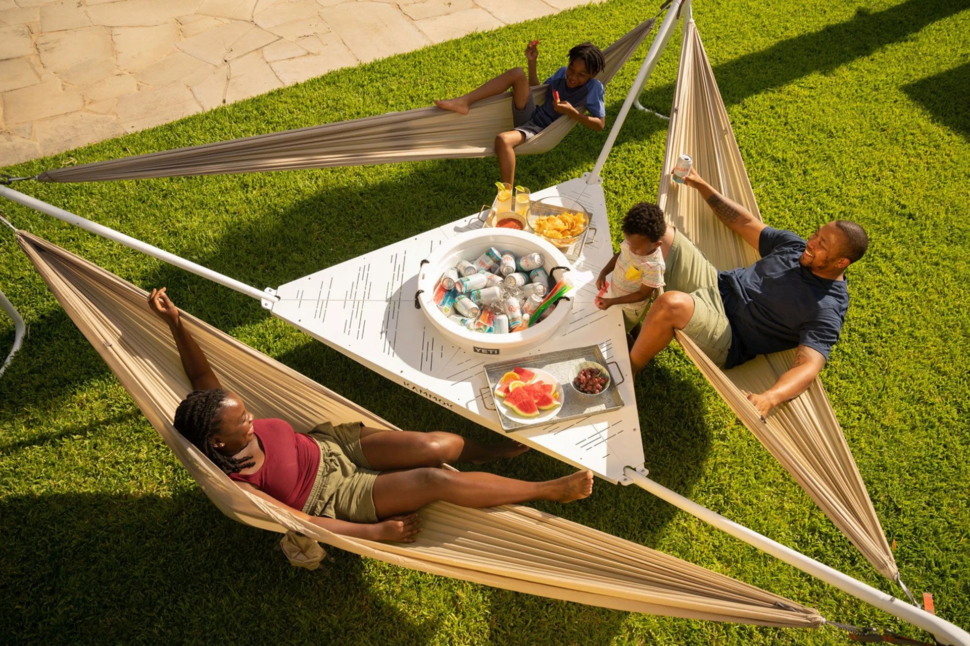 a family sitting in hammocks arond a table with food and drinks