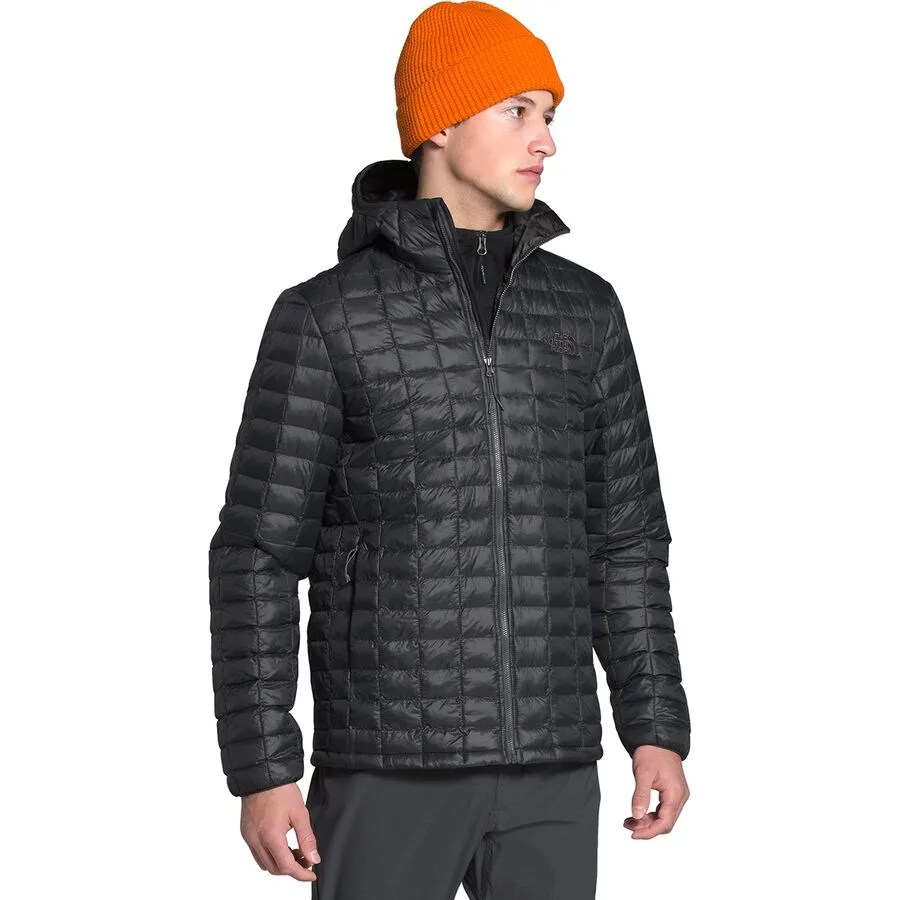 a man wearing a quilted black jacket and an orange hat