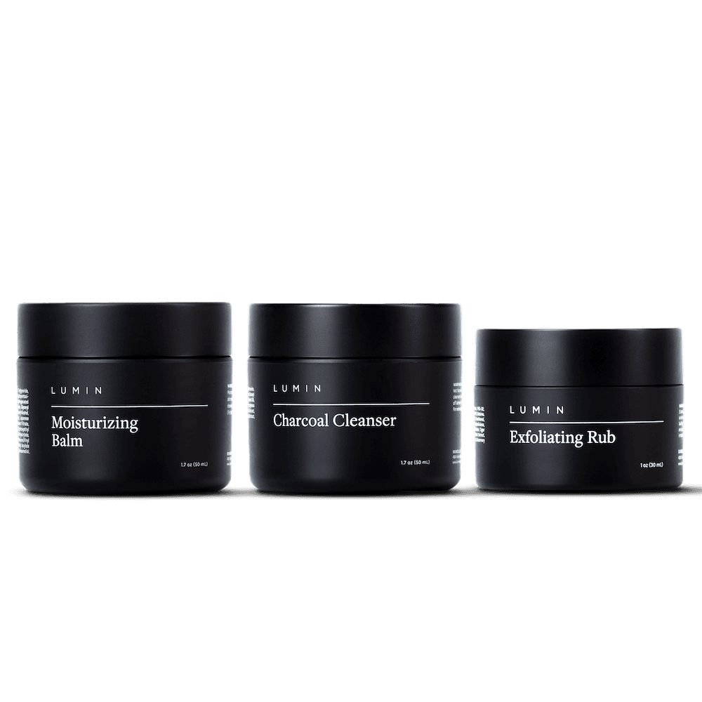 Three skincare products in black containers on a gray background.
