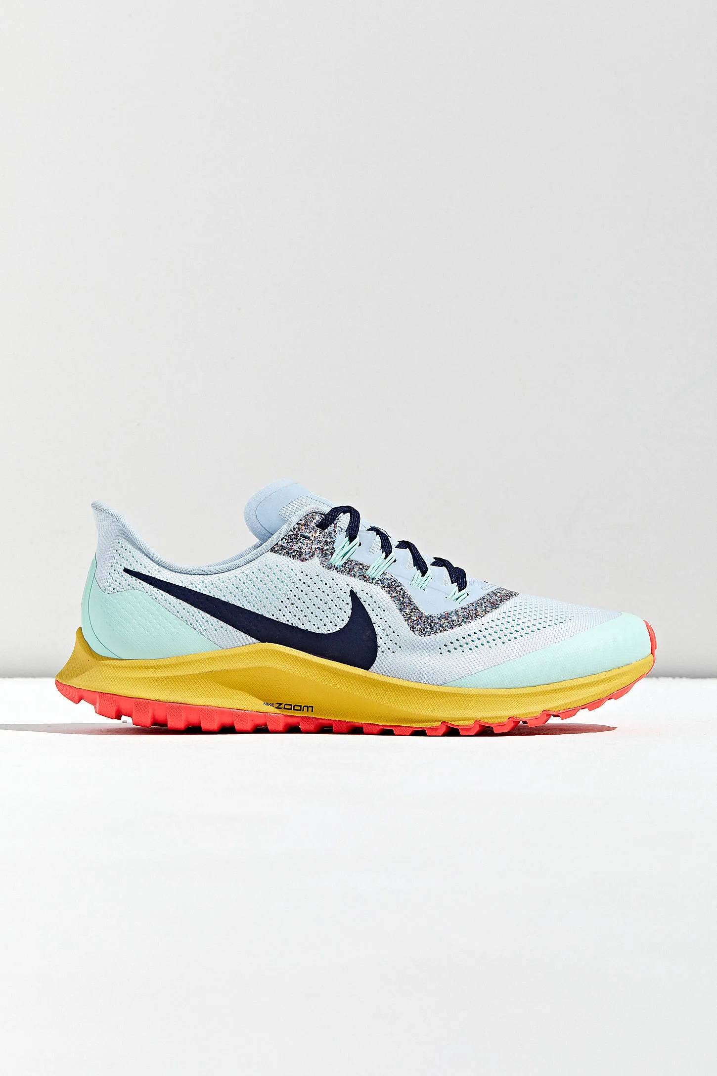 A multi-colored trail sneaker on a gray background.