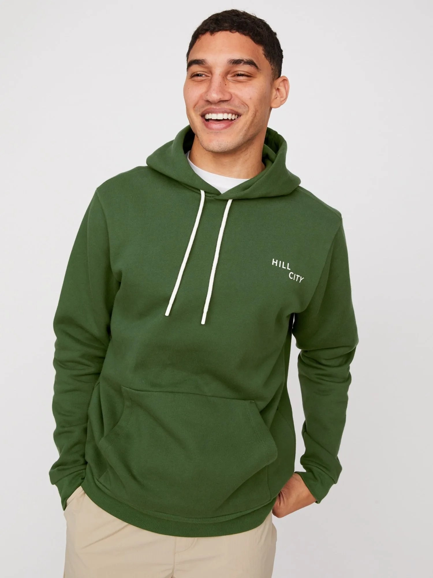 A model wearing a green hoodie on a gray background.