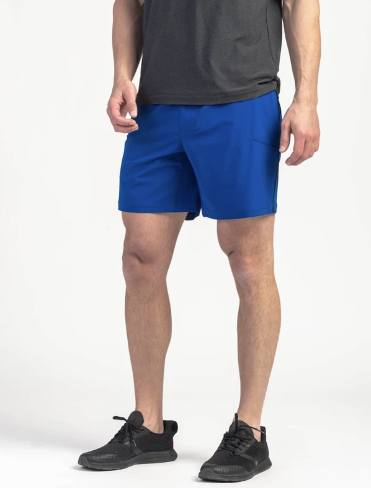 A model wearing blue shorts, a gray t-shirt and black sneakers on a gray background.