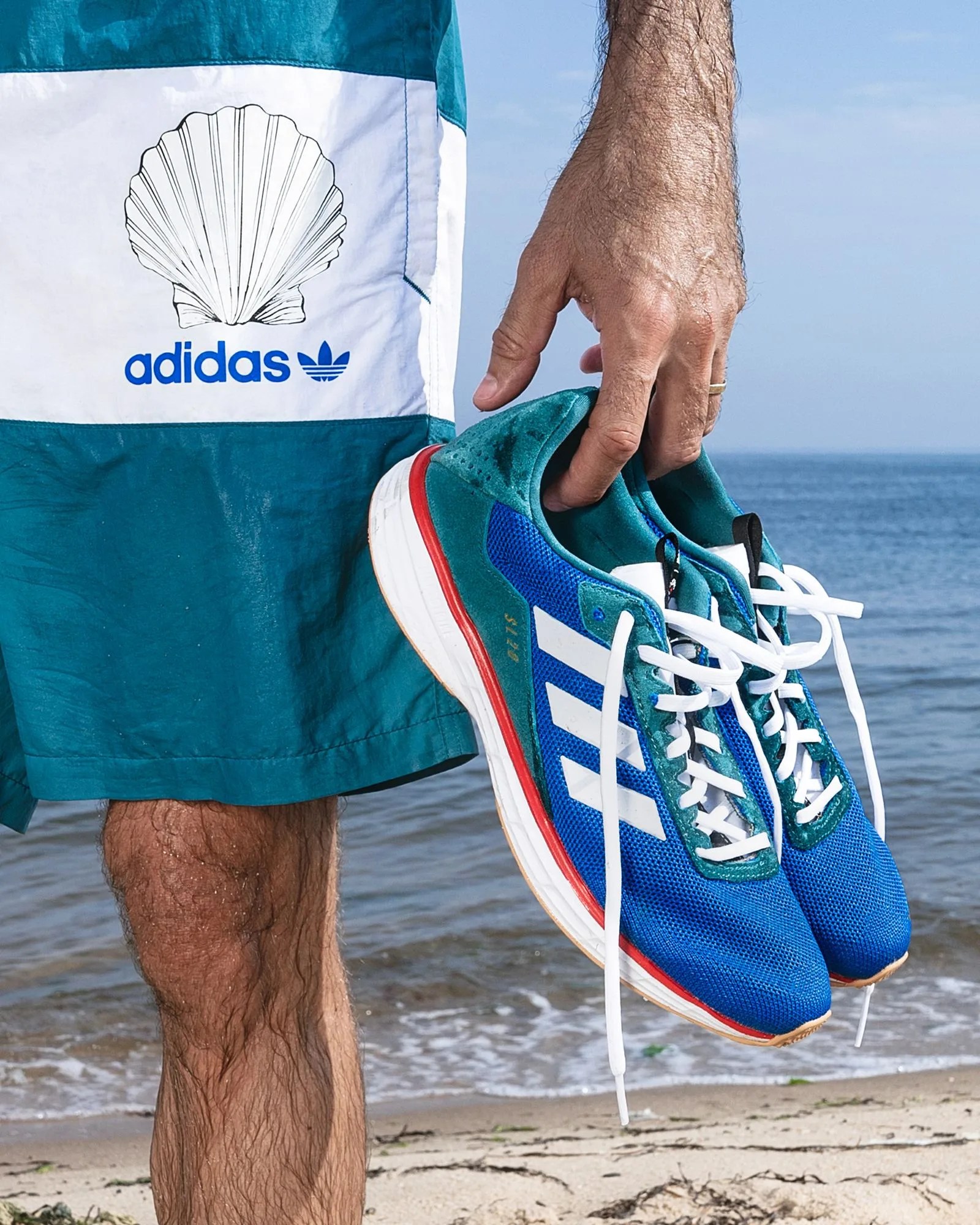person holding sneakers in front of the ocean