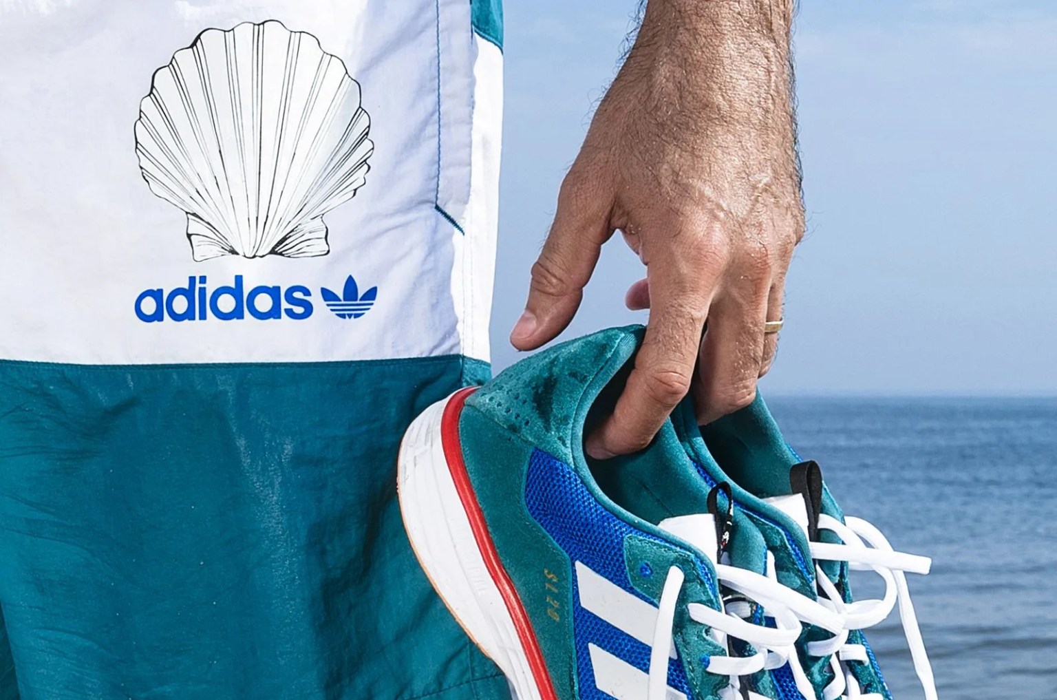 person holding sneakers in front of the ocean