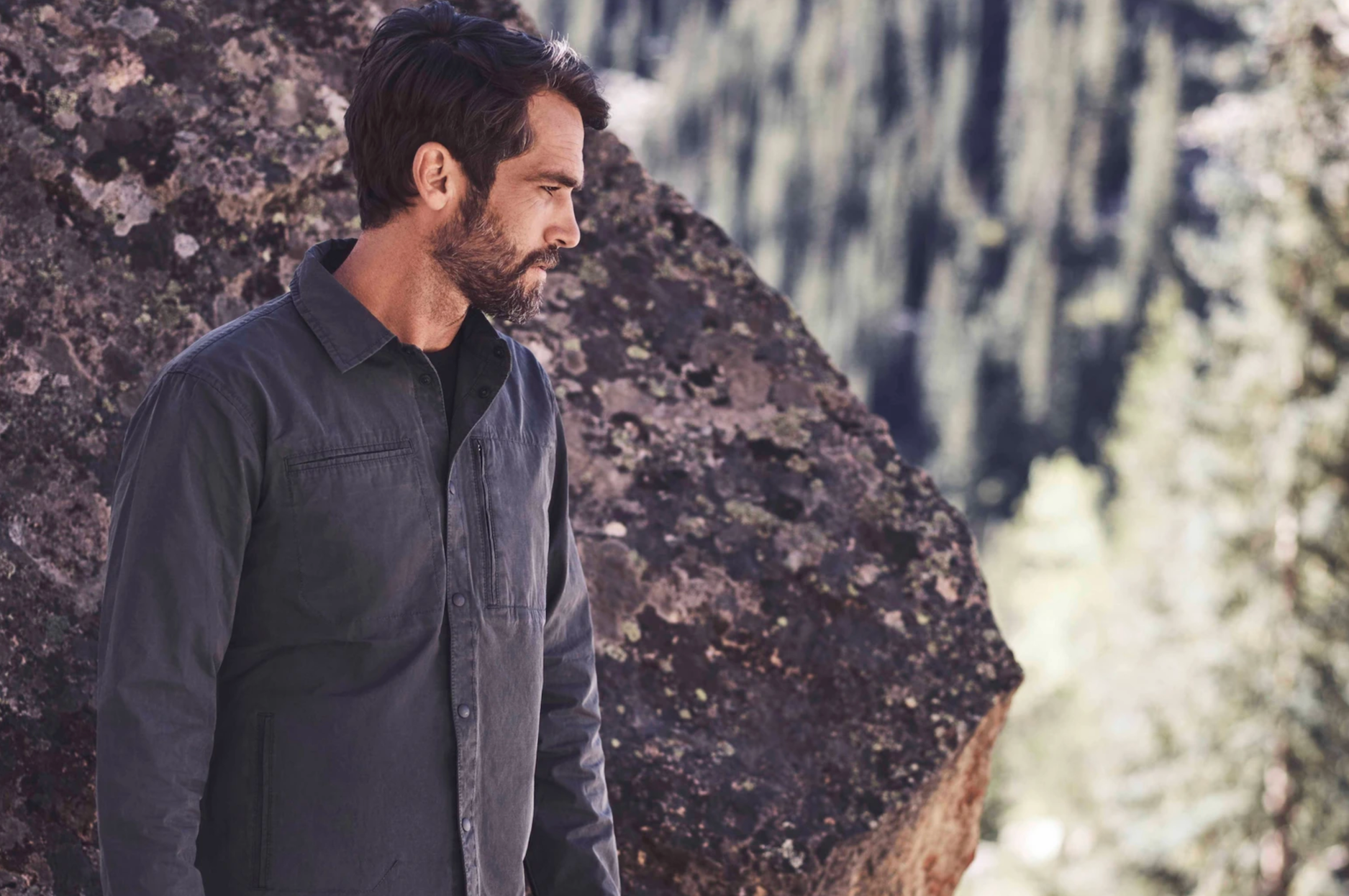 a model in front of a boulder wearing a graphite jacket