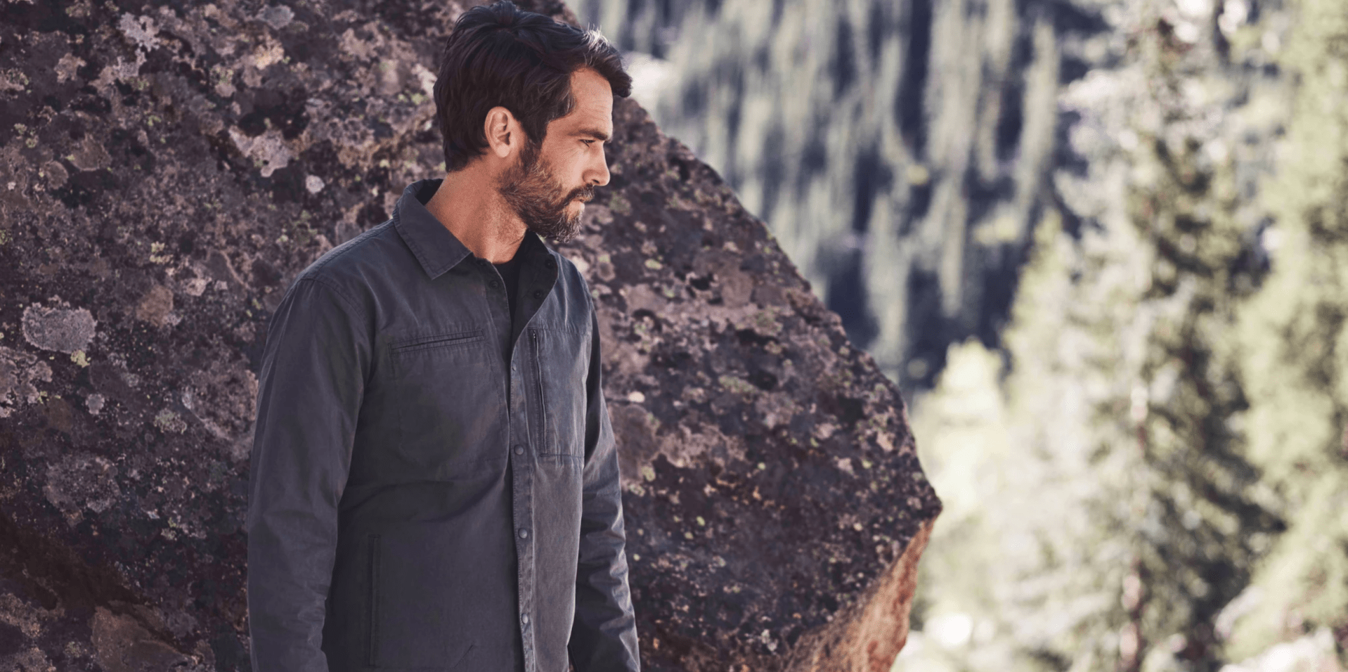a model in front of a boulder wearing a graphite jacket
