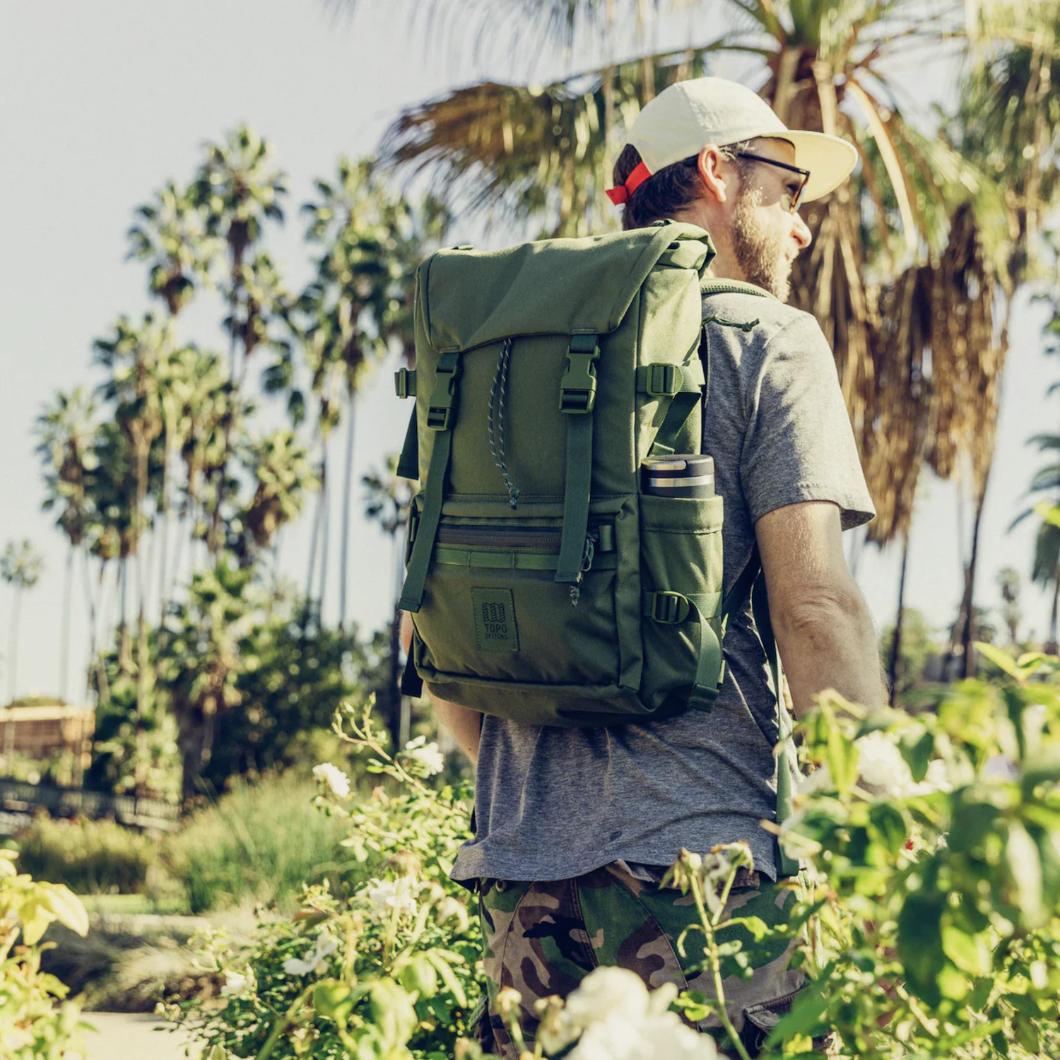 a model with an olive backpack in a jungle