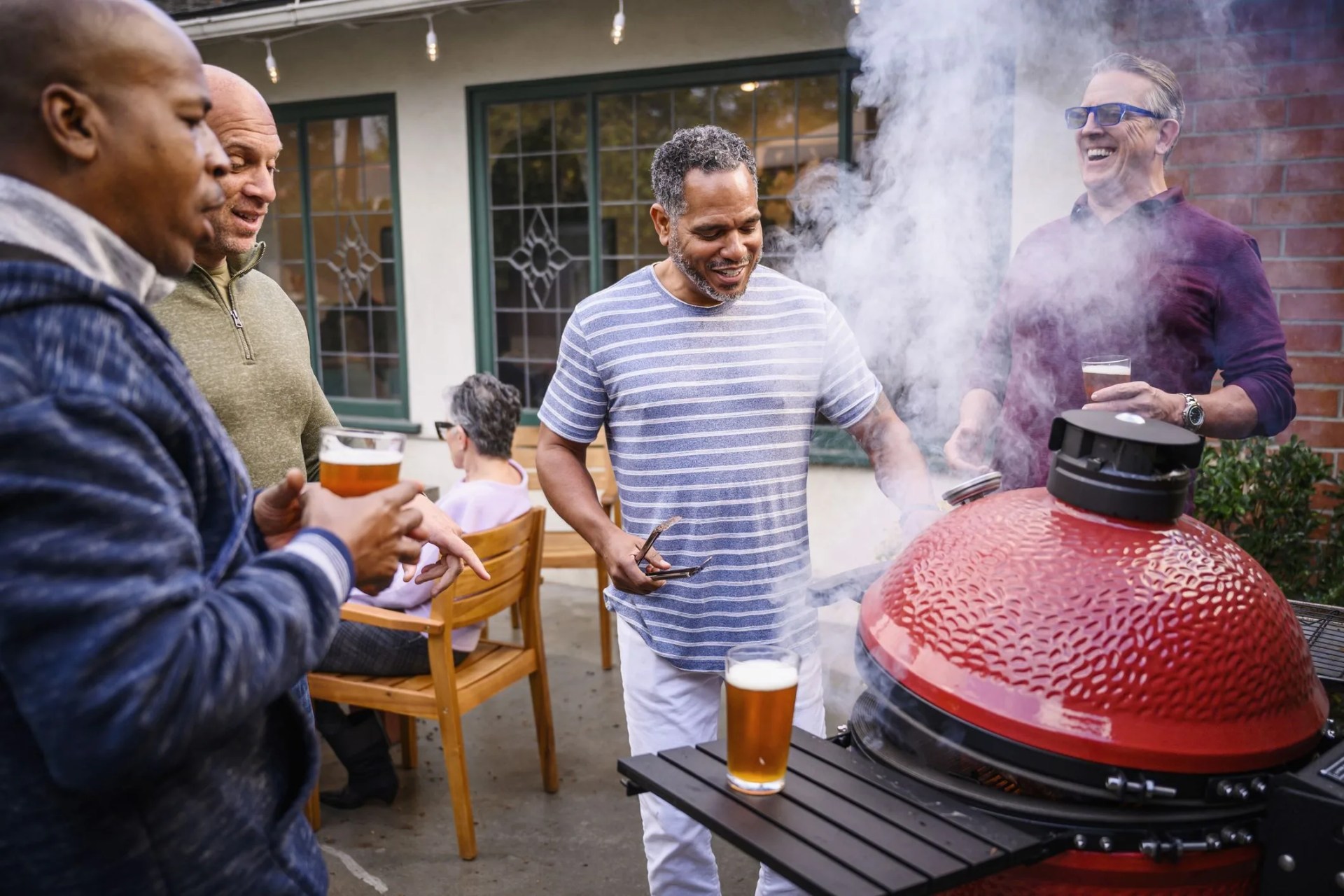mature men standing by barbecue grill talking
