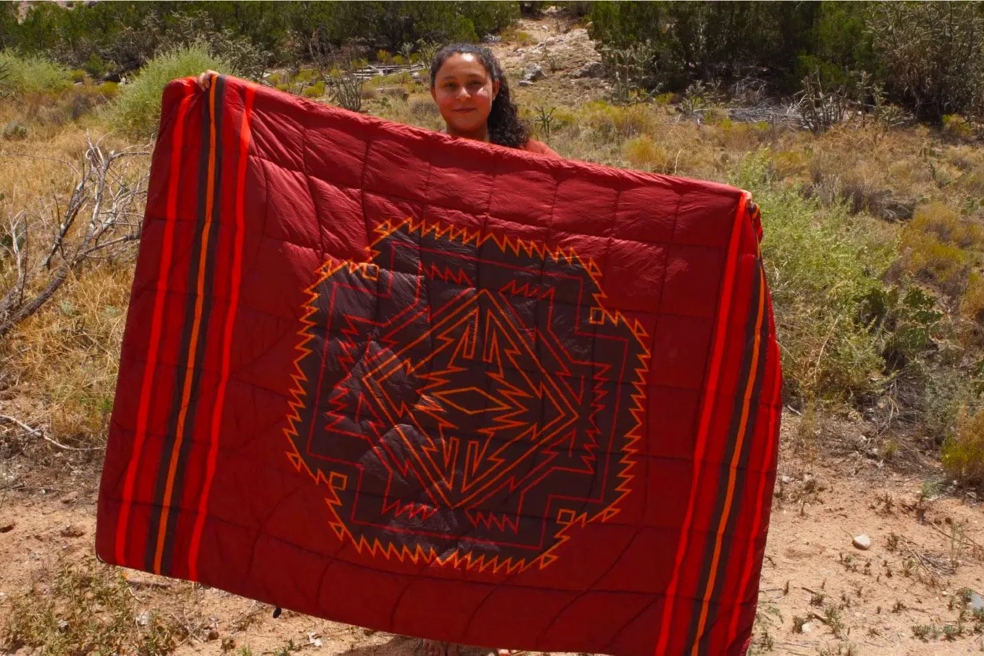 a woman holding up a red patterned blanket