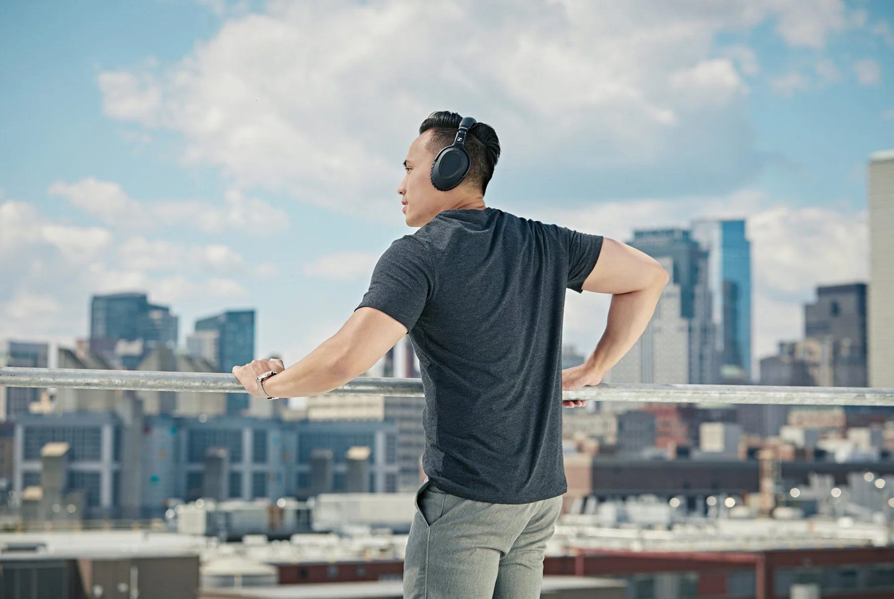 a model wearing a pair of black wireless headphones standing on a rooftop
