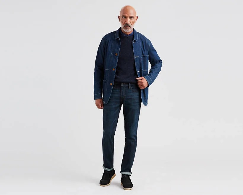 A model wearing blue jeans, a blue sweater and a denim chore coat.