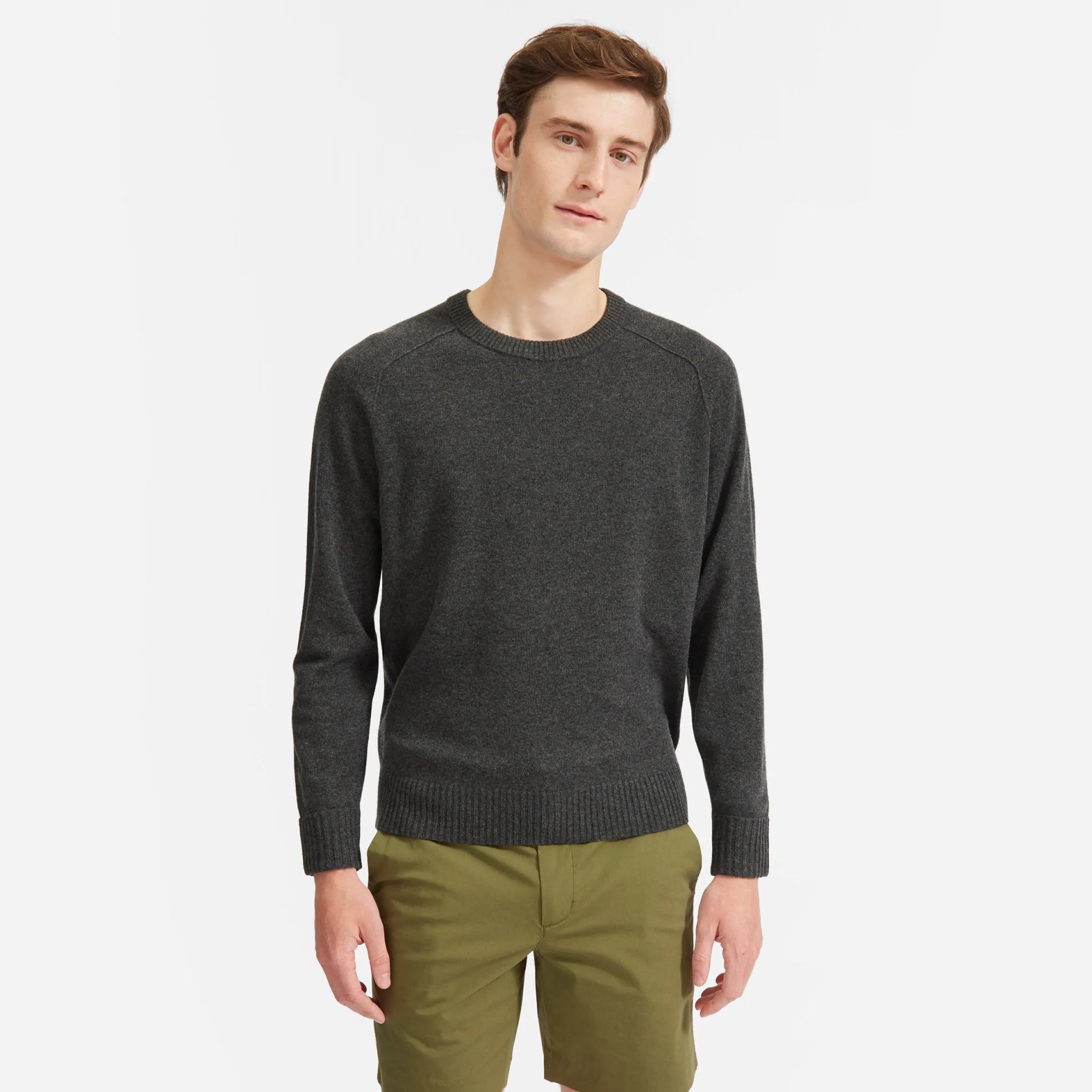 A model wearing a gray sweater and green pants on a gray background.