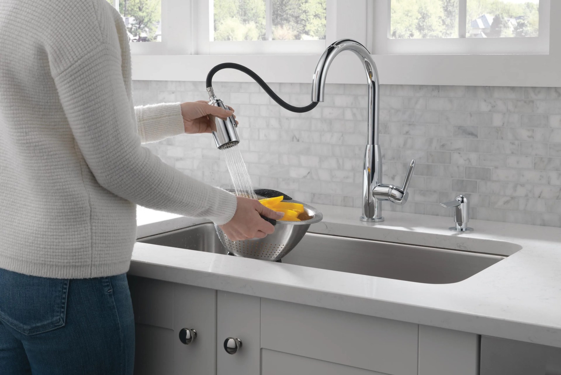 a model using a kitchen sink to clean vegetables