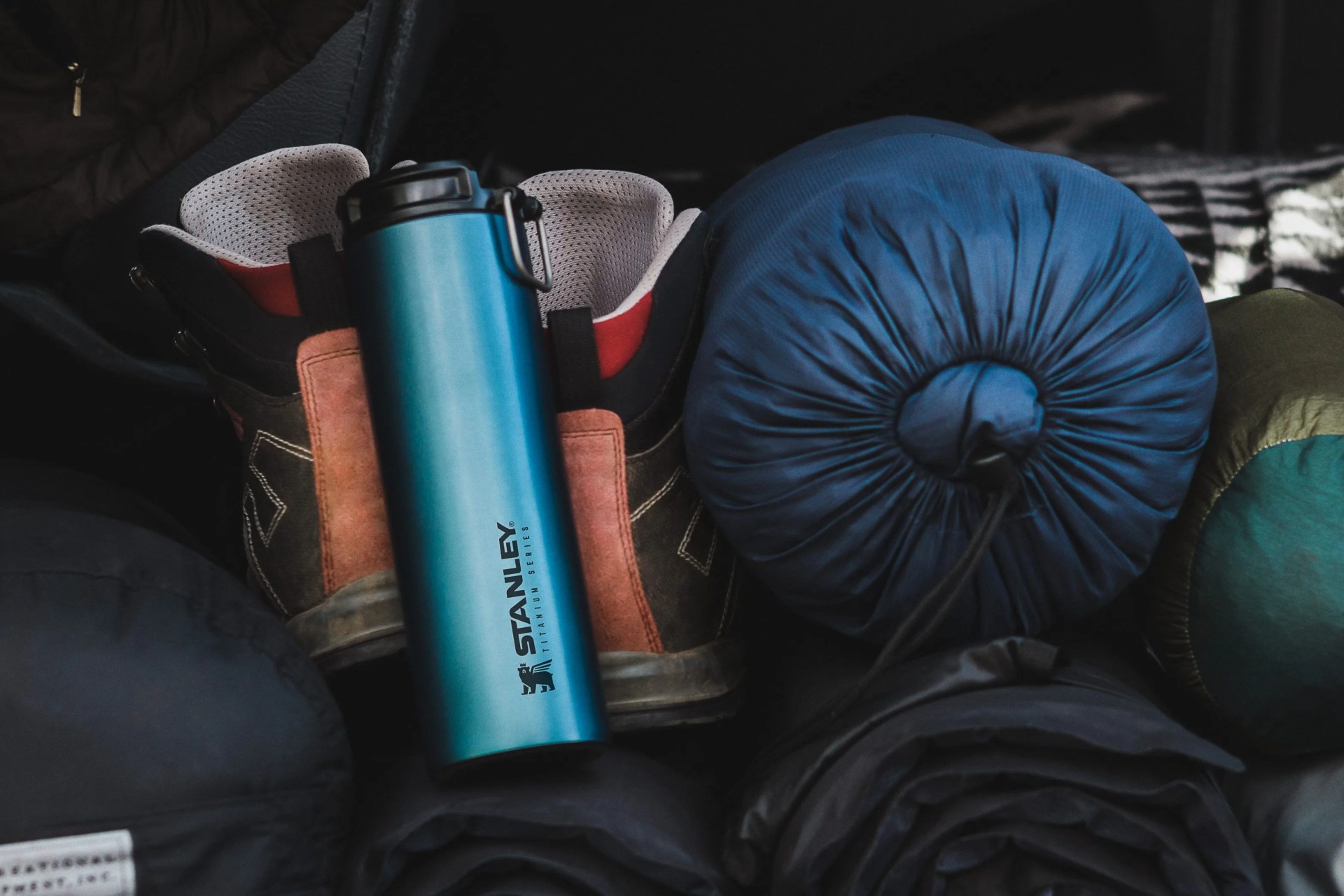 a blue insulated mug next to hiking boots