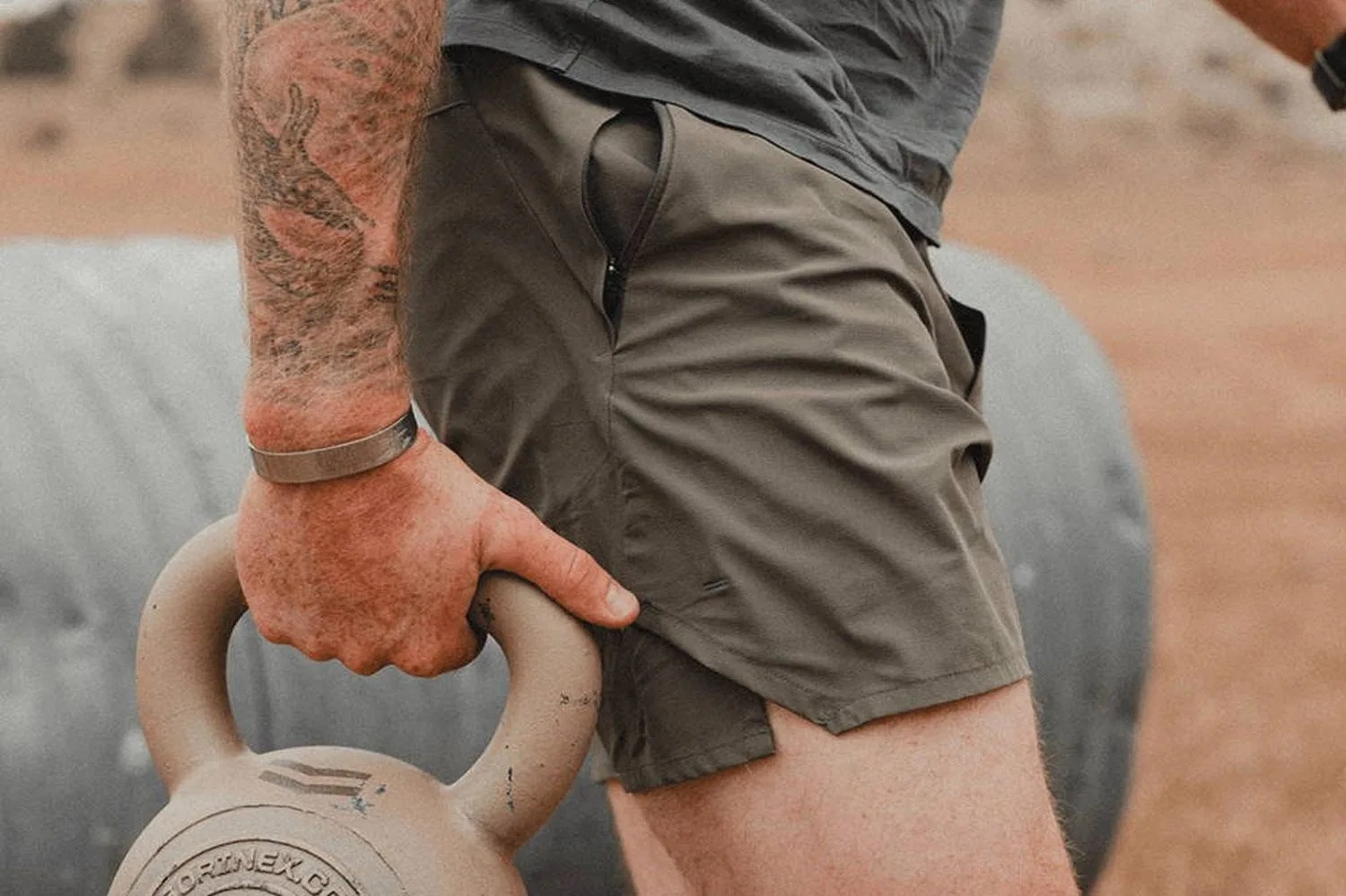 a man wearing olive shorts carrying a weight