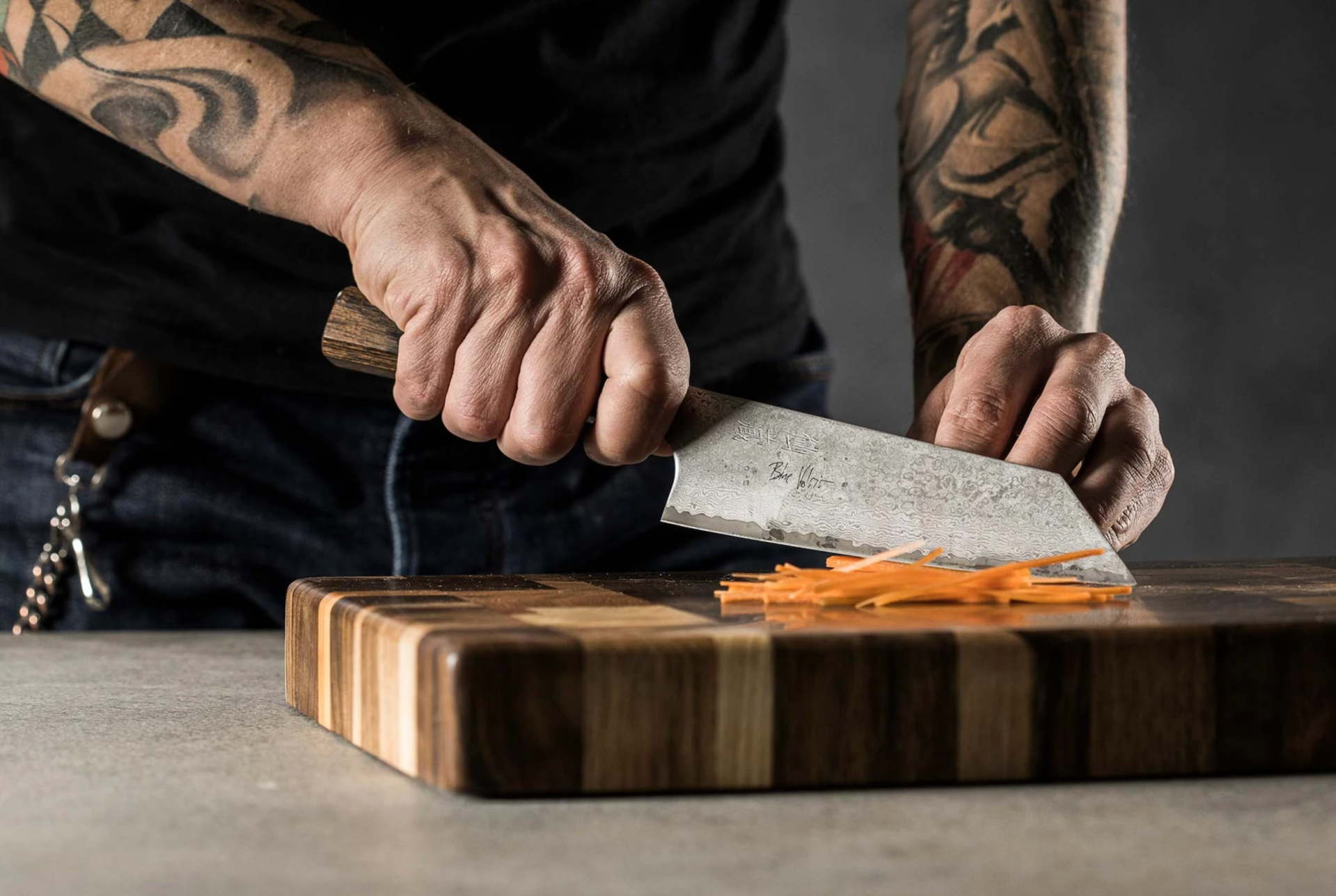 a man using a japanese knife to cut vegetables on a cutting board