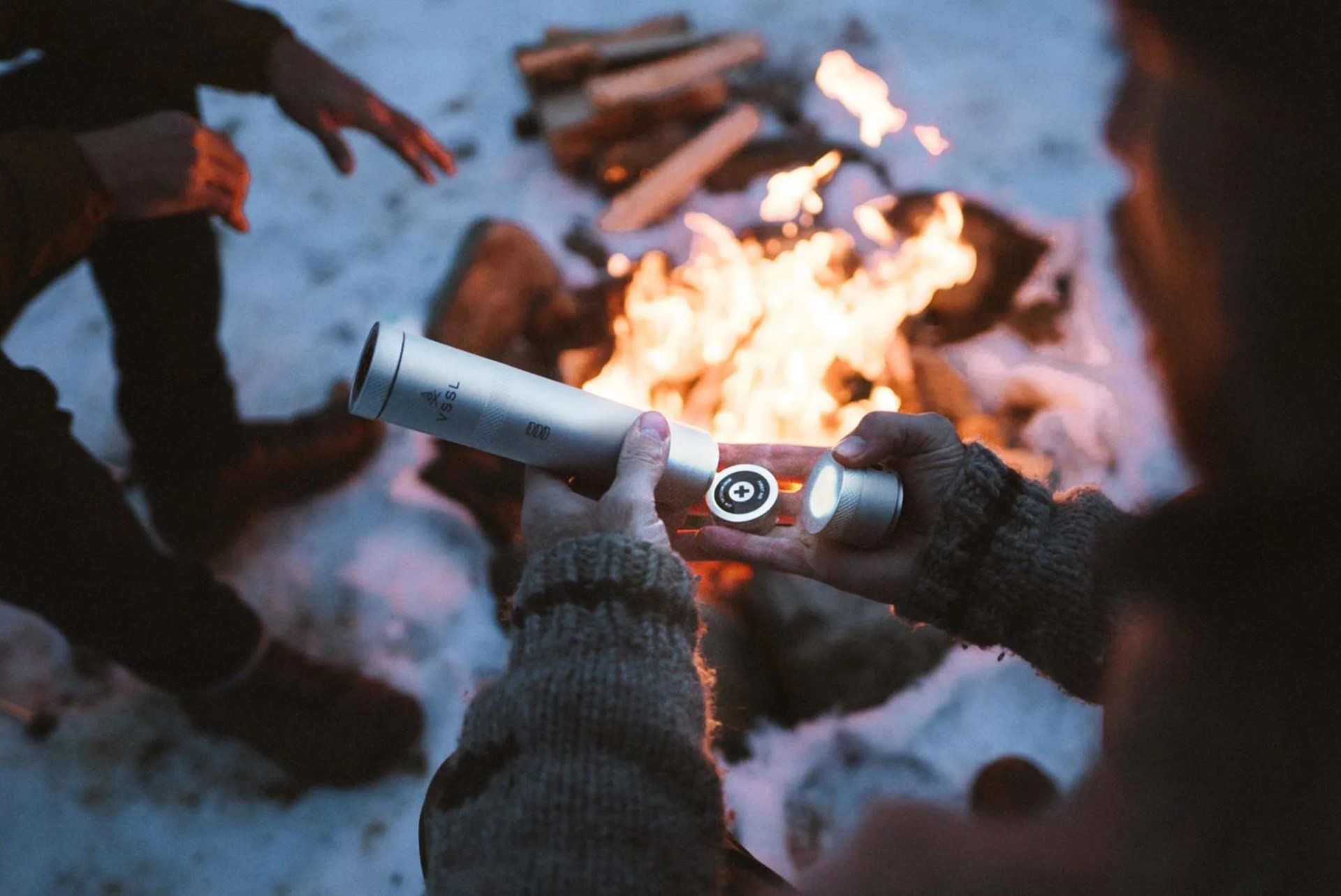 a man opening a metal cylinder near a campfire
