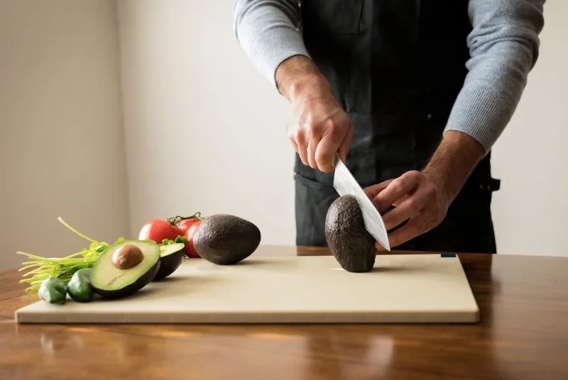 man cutting avocado on cutting board