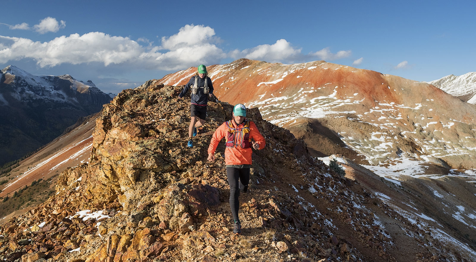 two people running on a rocky ridge
