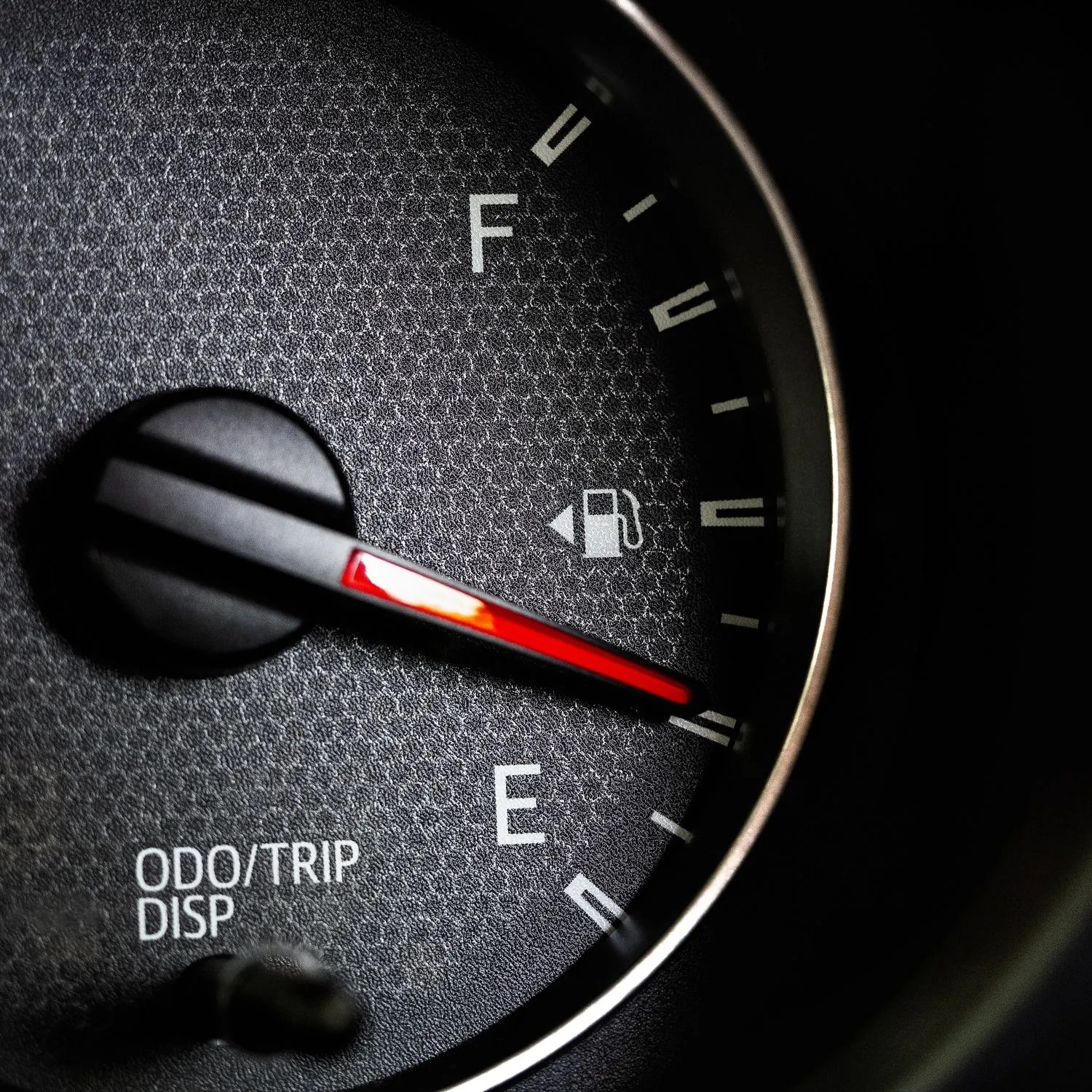 close up of car fuel gauge with red needle
