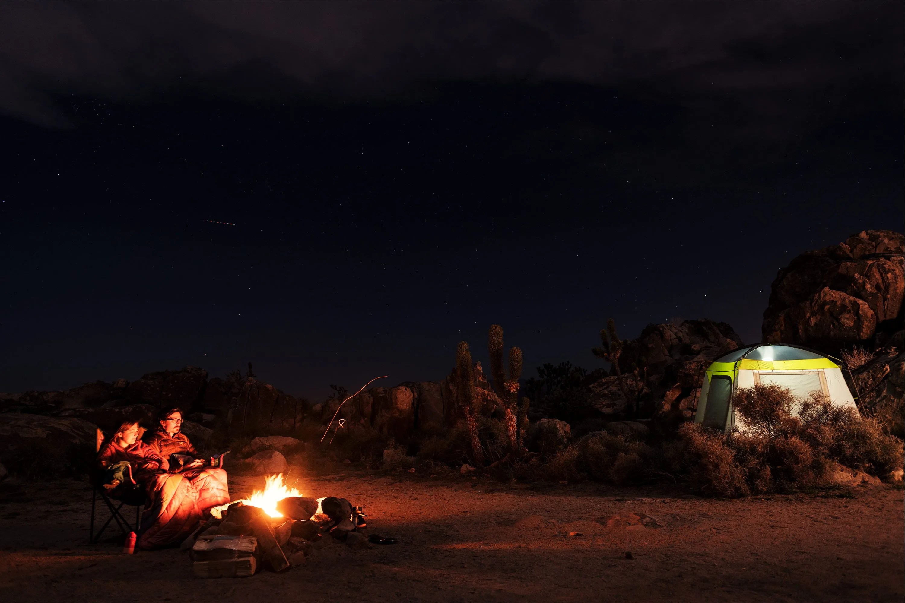 backcountry two people warming themselves by the fire at night