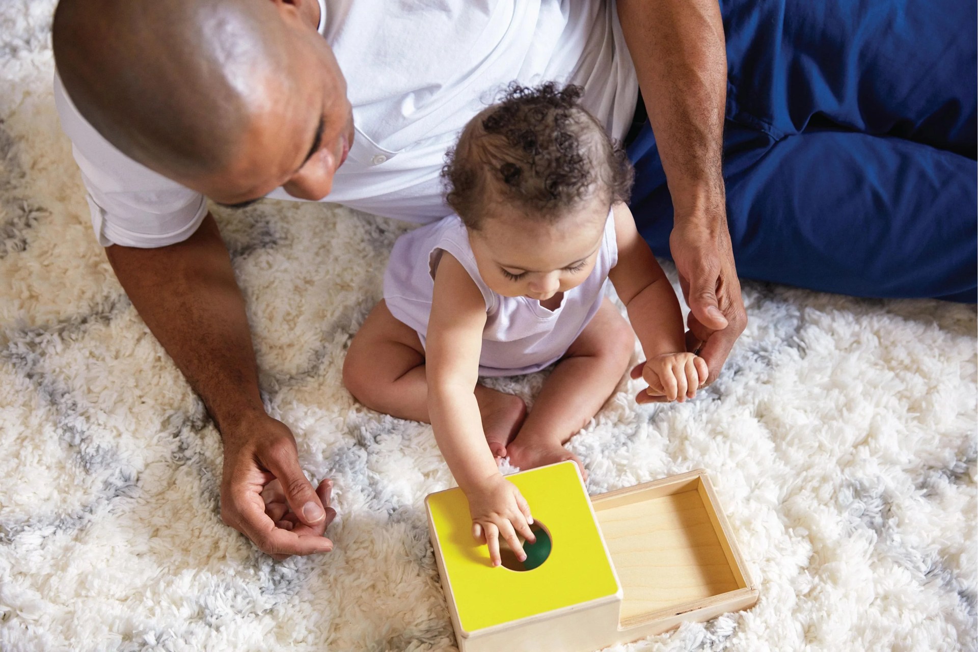 dad supervising kid playing with lovevery toy