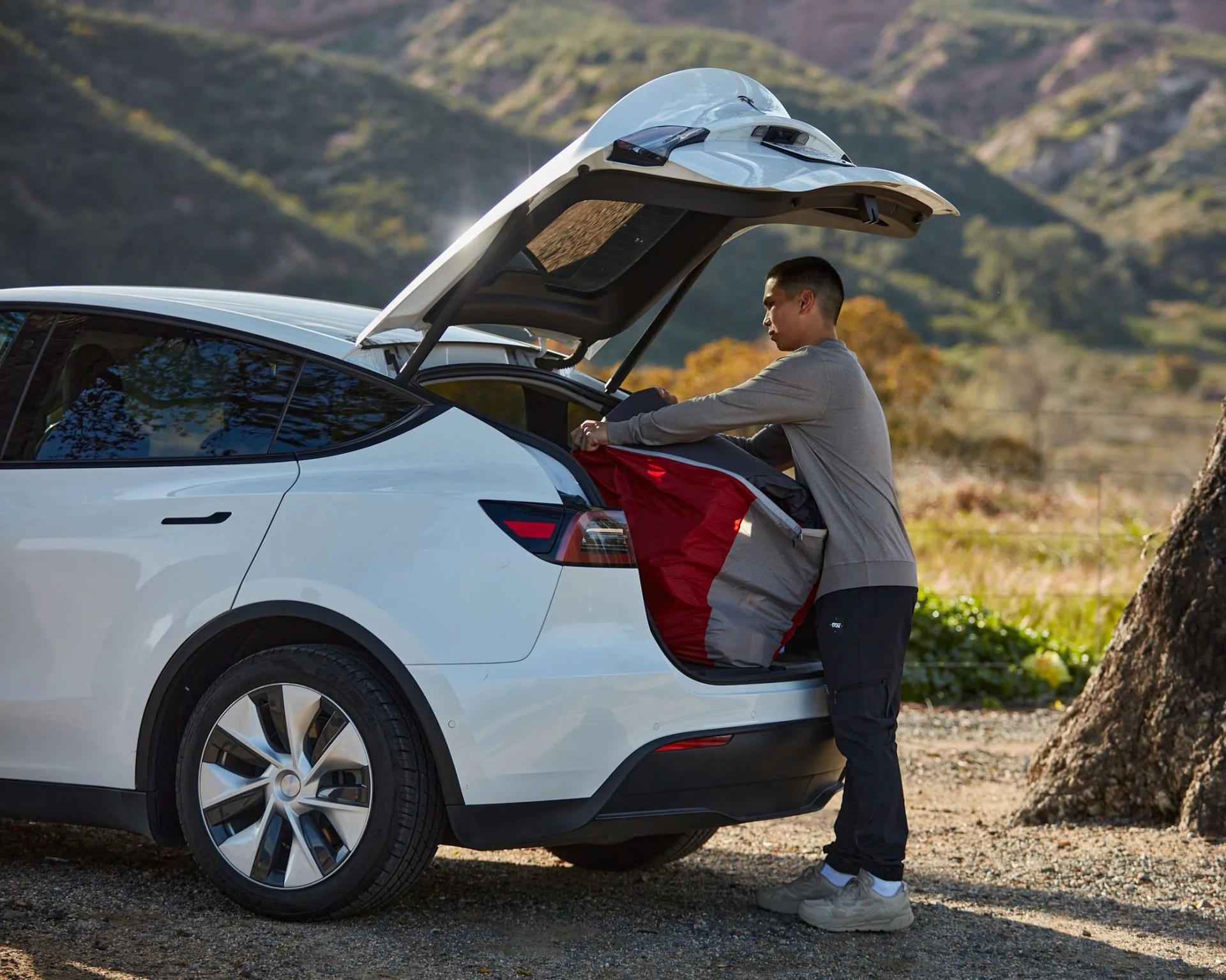 man packing trunk of a white SUV on side of the road