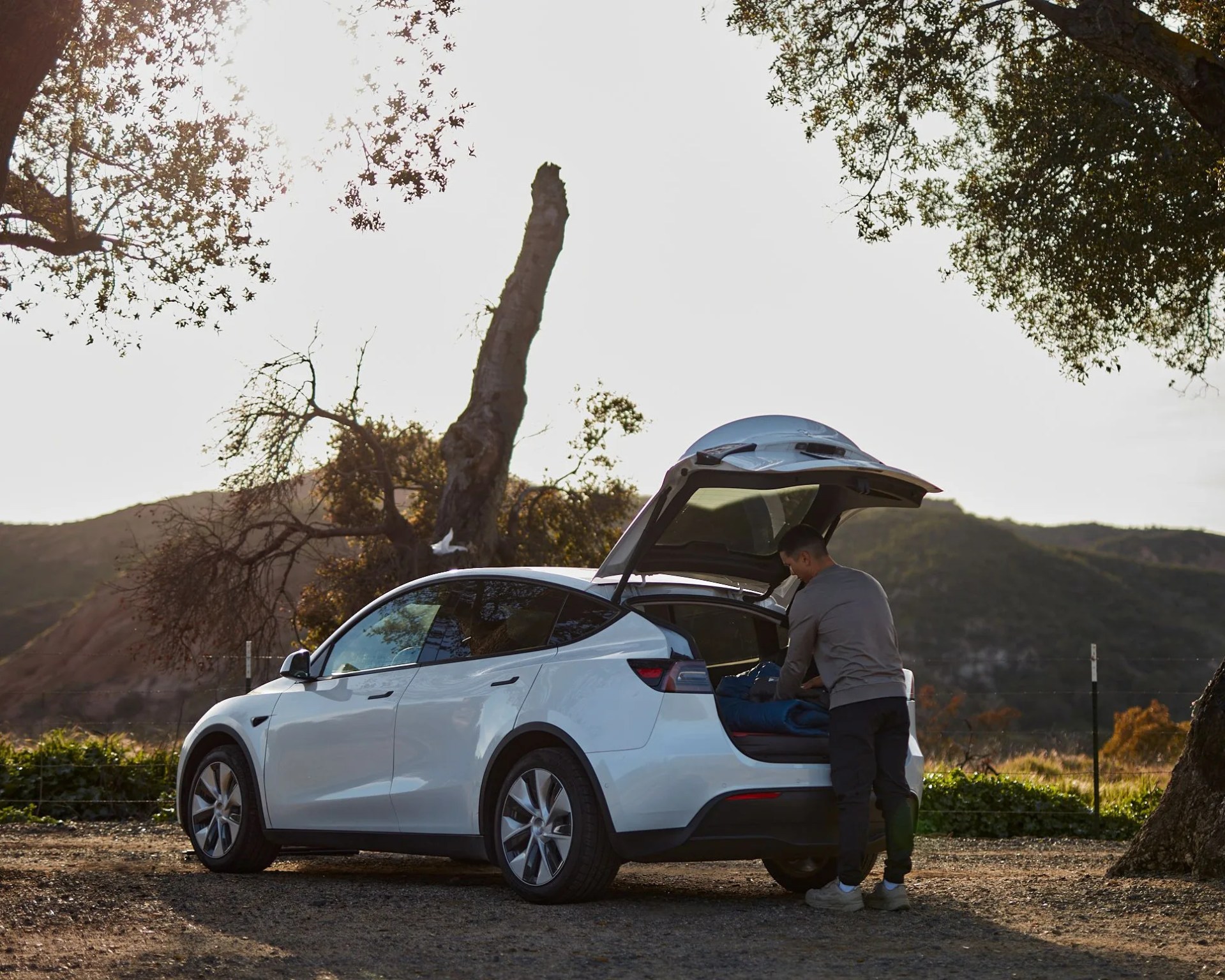 man packing trunk of a white SUV on side of the road