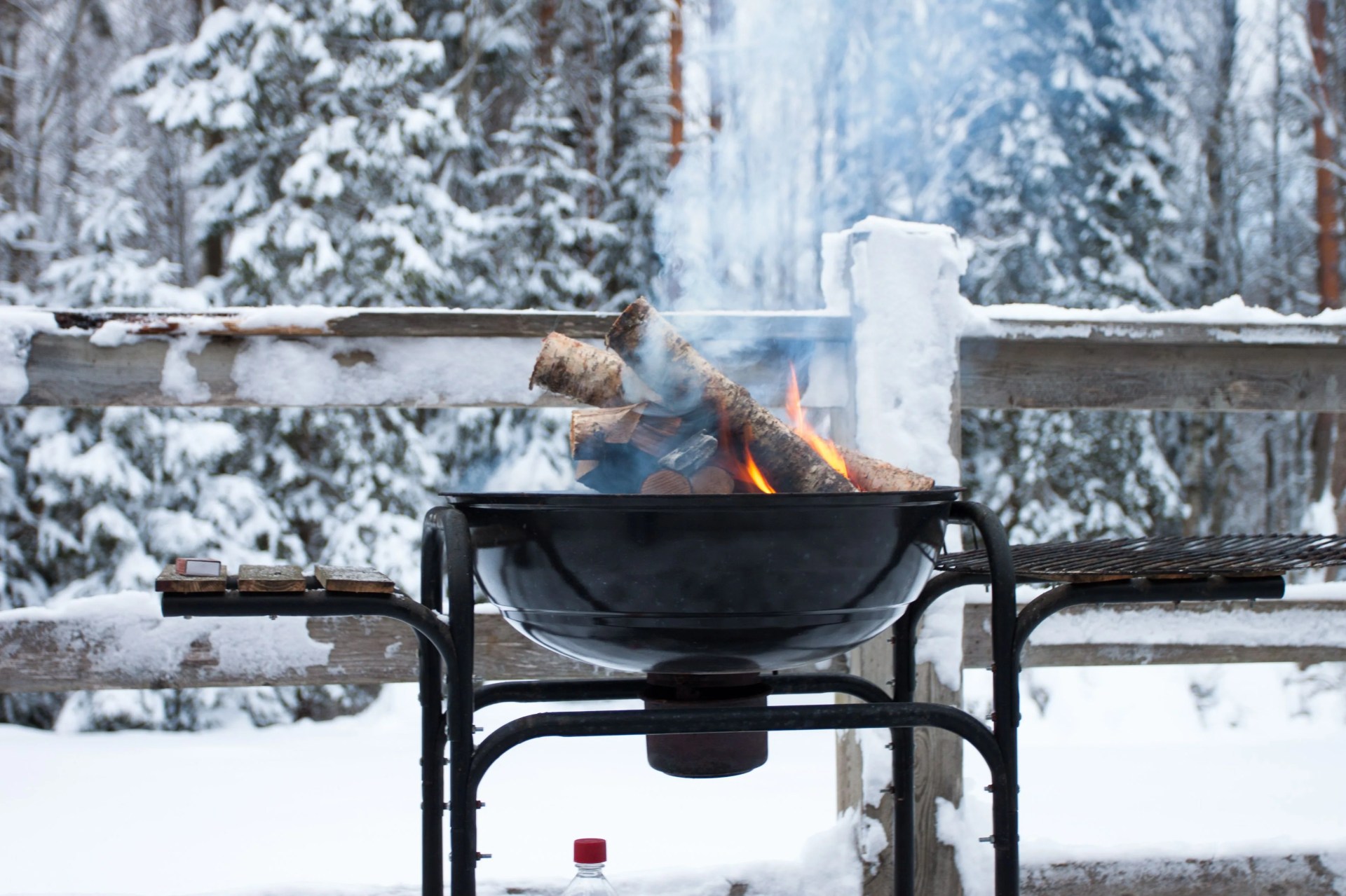 metal basket with a glowing wood camp fire at a cold winter day in forest