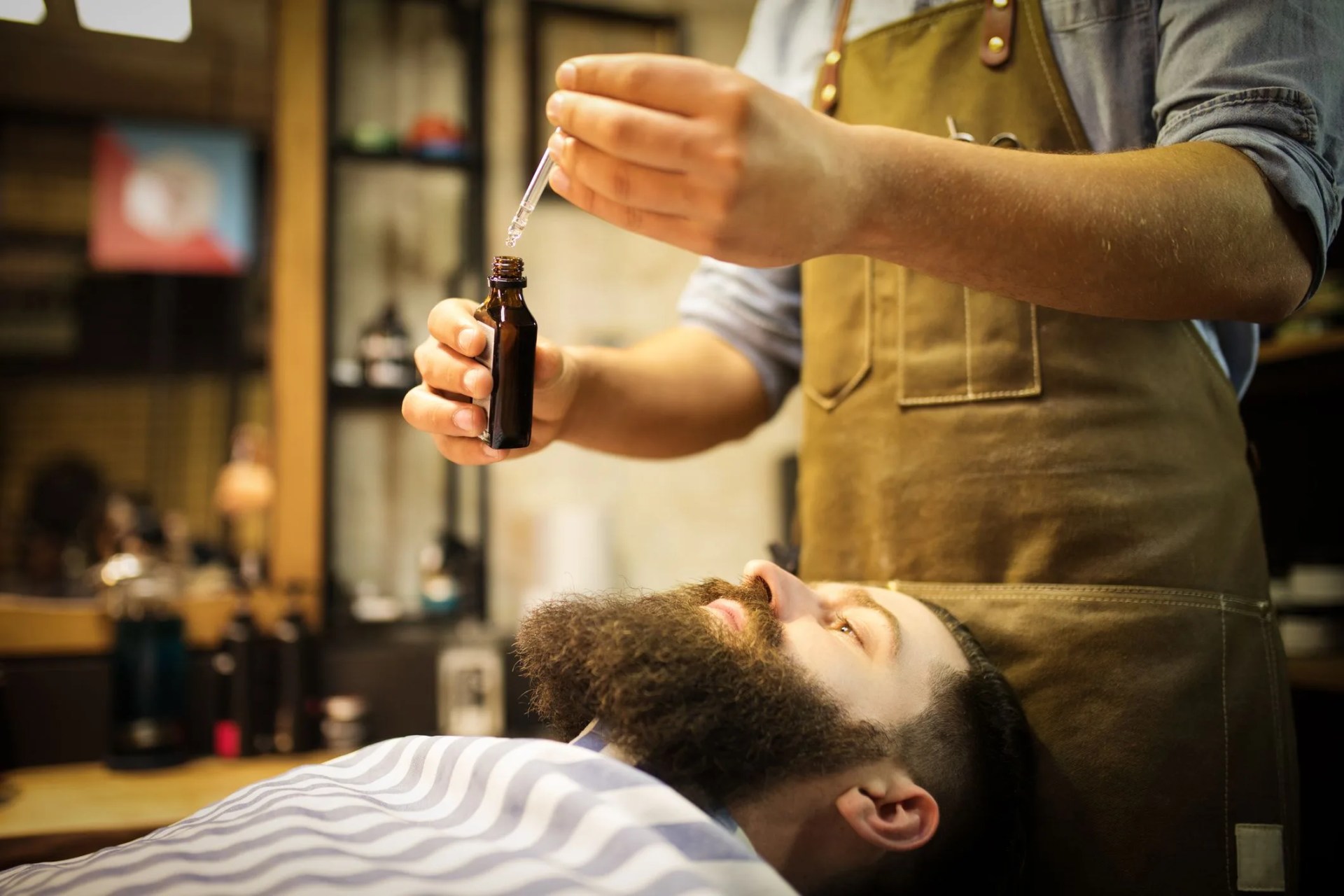 barber putting beard oil to client