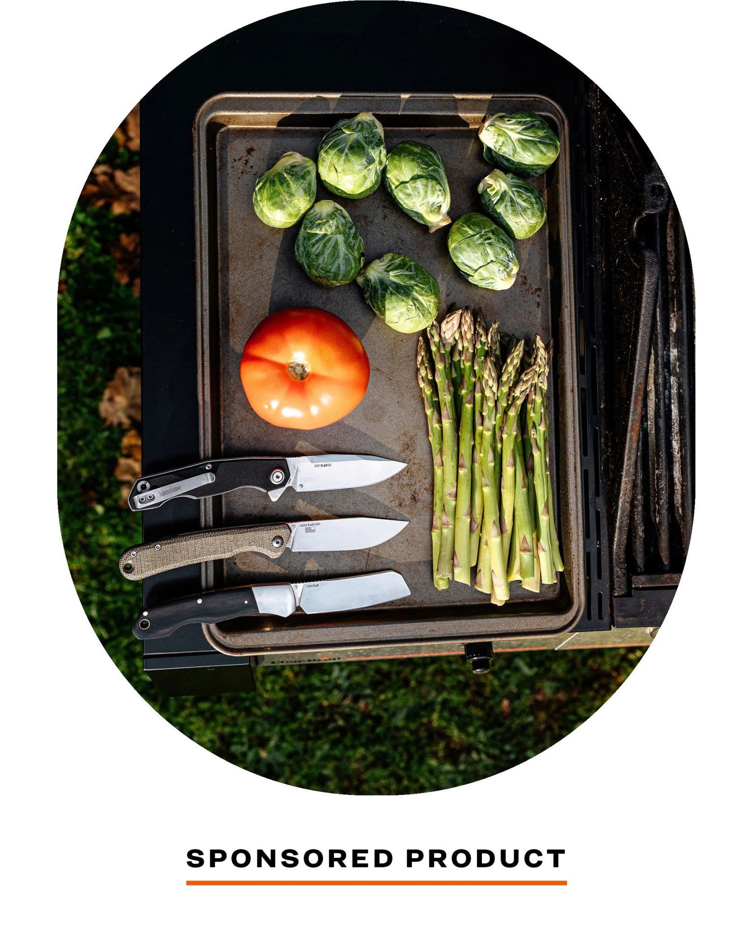 kershaw knives laying next to some brussel sprouts, tomato, and asparagus on baking tray