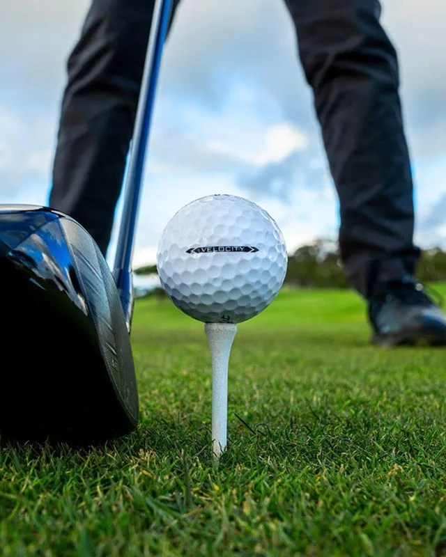 person standing on grass about to hit a velocity golf ball