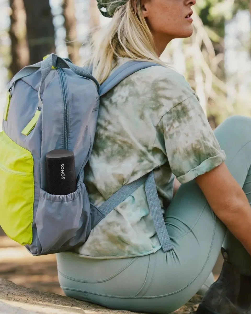 woman carrying sonos roam sl speaker in her backpack