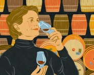 woman smelling whiskey with barrels in the background