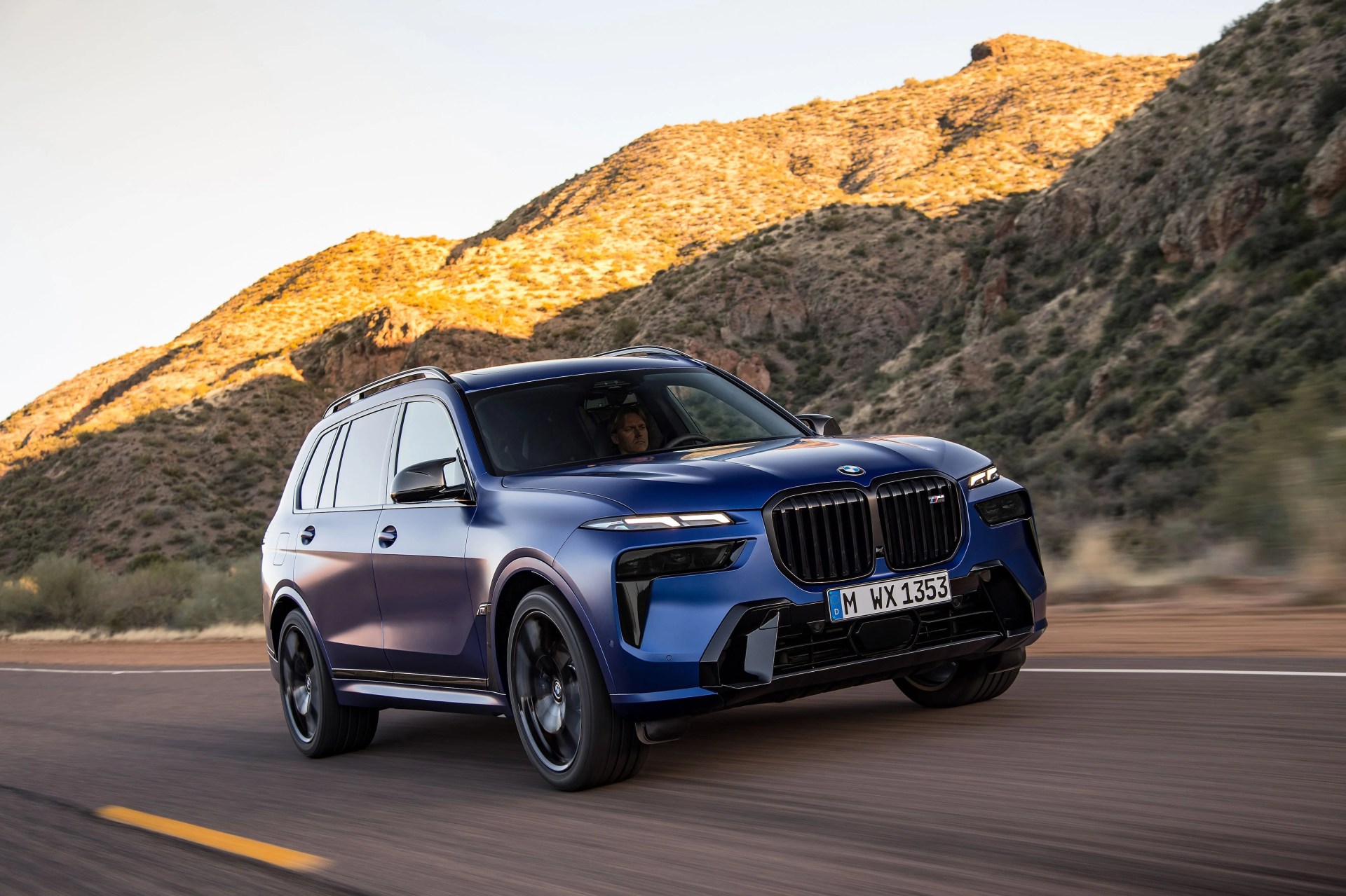 the new bmw x7 driving along a highway with mountains in the background