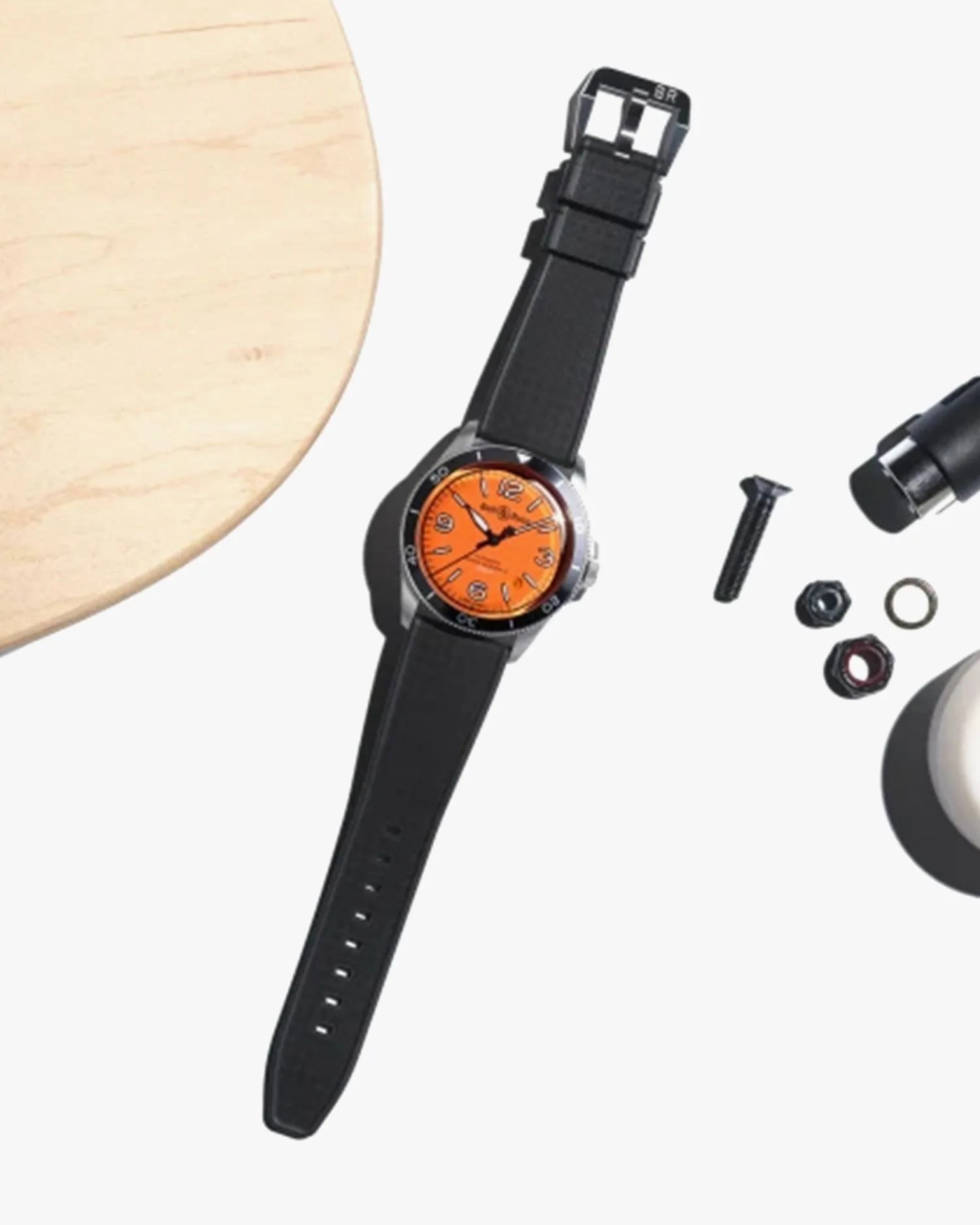 bell and ross watch laying next to nuts, bolts, and screws