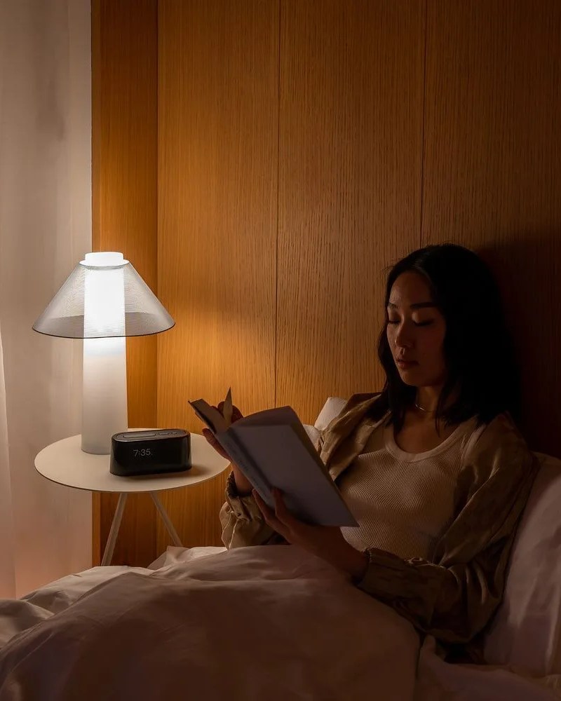 woman reading in bed using her loftie lamp