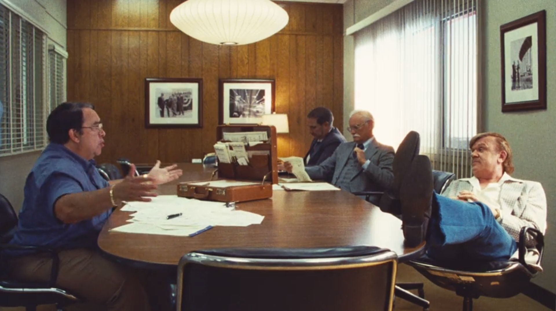 men sitting around a table with a lamp hanging overhead