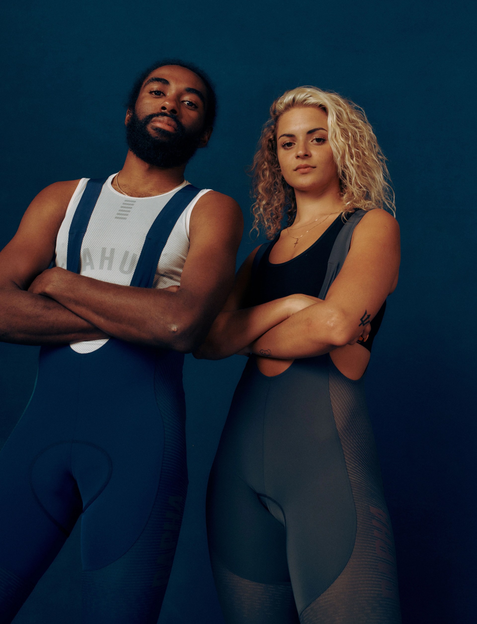 man and woman standing side by side with their arms crossed wearing rapha performance shorts