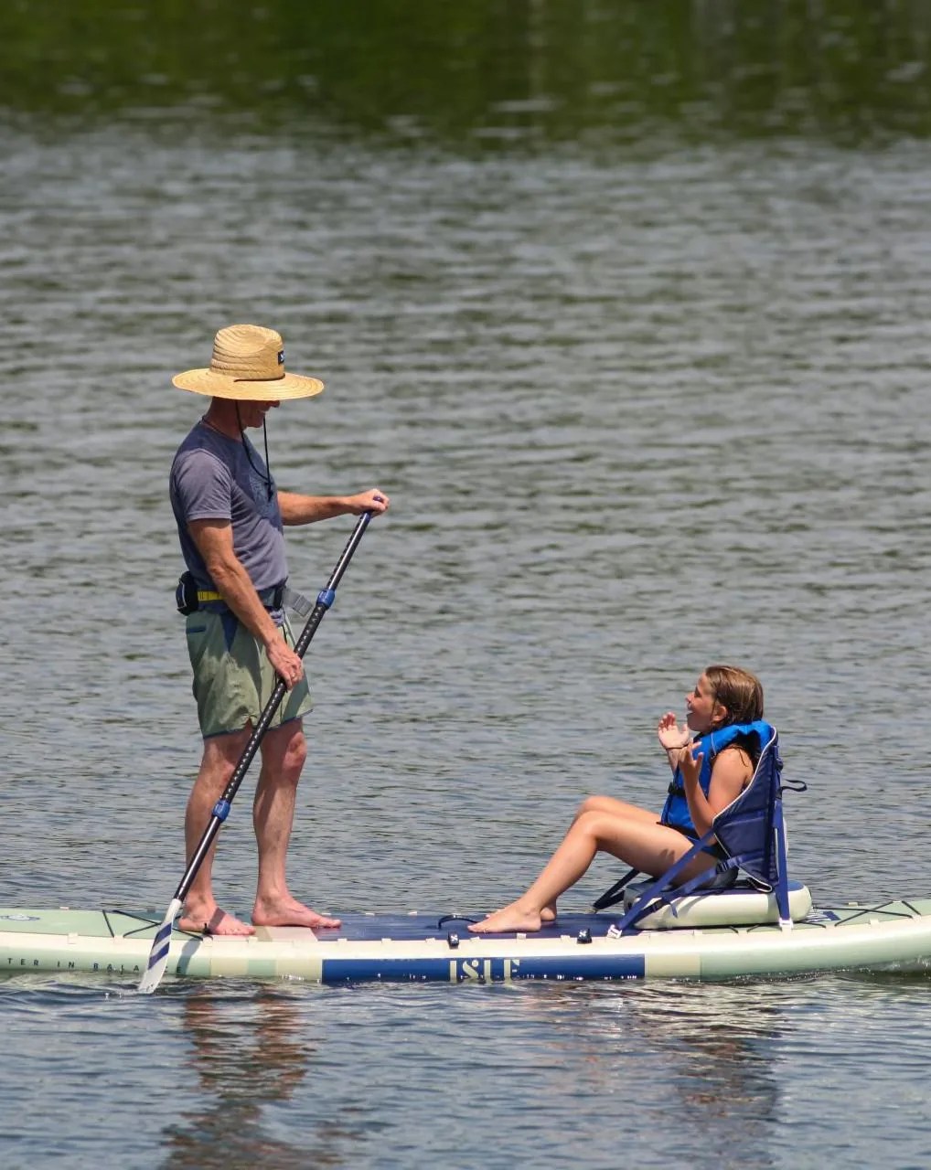 man standing on paddle board with daughter