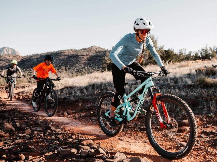 woman riding on bike with two kids following