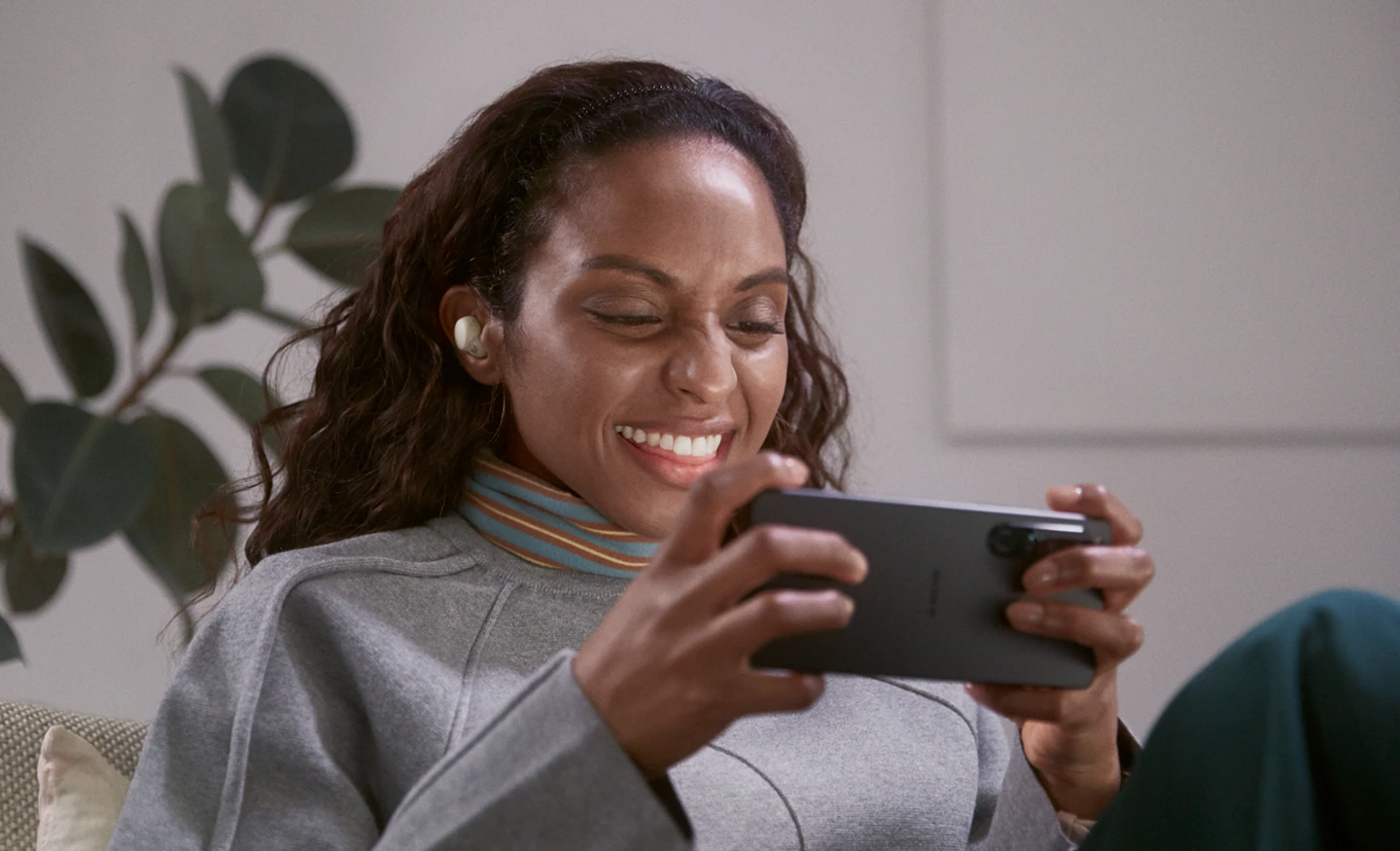 smiling woman wearing sony linkbuds s and playing on her phone