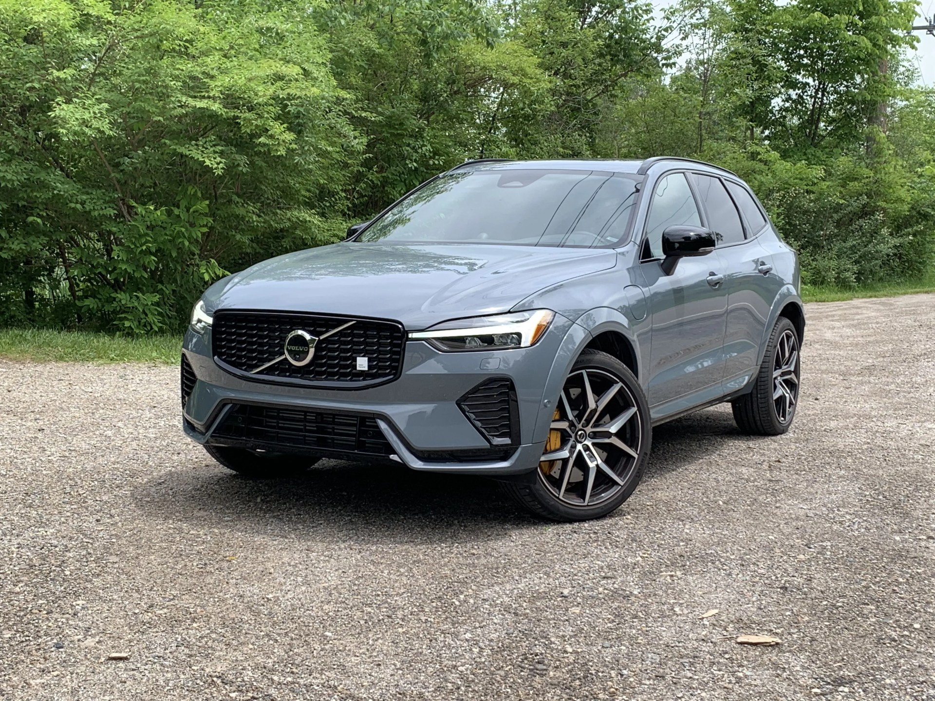 volvo xc60 recharge parked on gravel in front of a forest