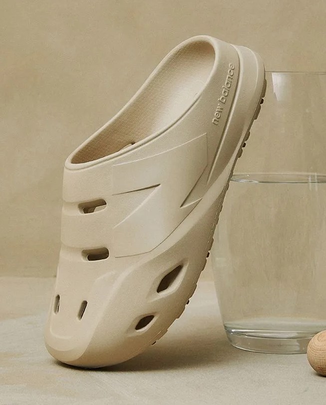 new balance clog resting against glass of water next to two wooden balls